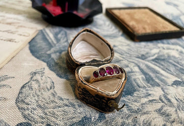 La Rosa ~ Anillo antiguo de la época eduardiana con cinco rubíes engastados en media alianza y galería con volutas, estilo victoriano, oro de 9 quilates.