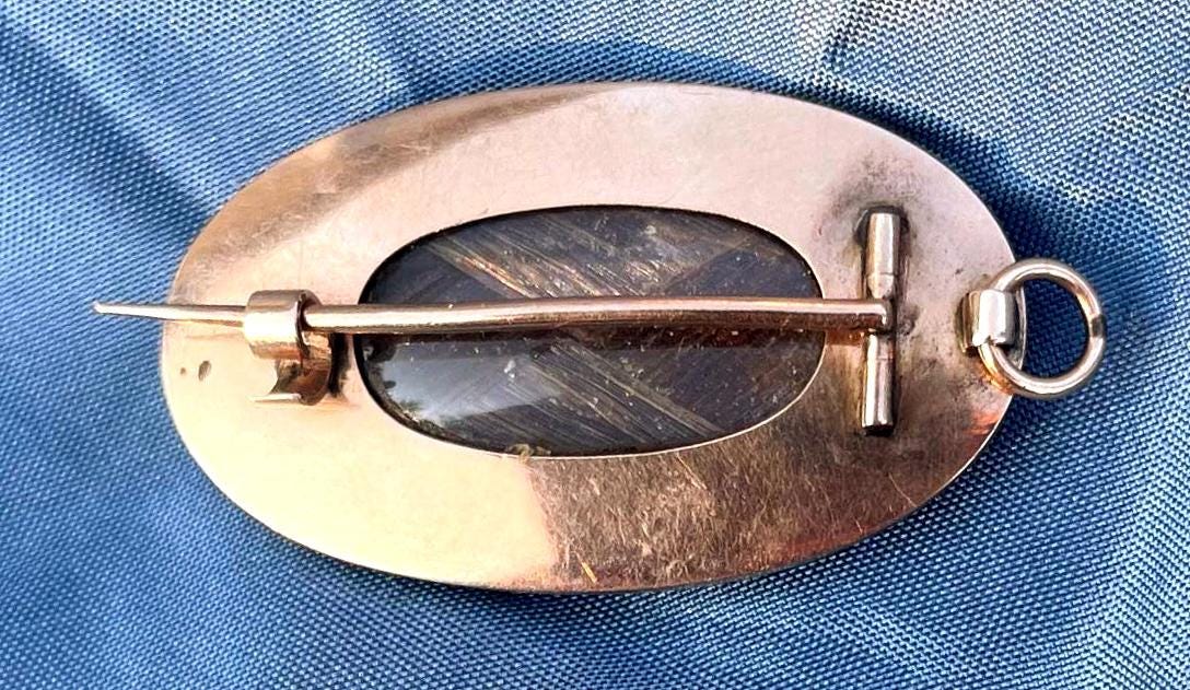 Broche relicario de luto georgiano antiguo del siglo XVIII en oro con esmalte blanco, perla, cabello y motivo de urna.
