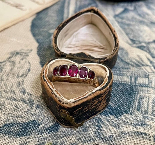 La Rosa ~ Anillo antiguo de la época eduardiana con cinco rubíes engastados en media alianza y galería con volutas, estilo victoriano, oro de 9 quilates.